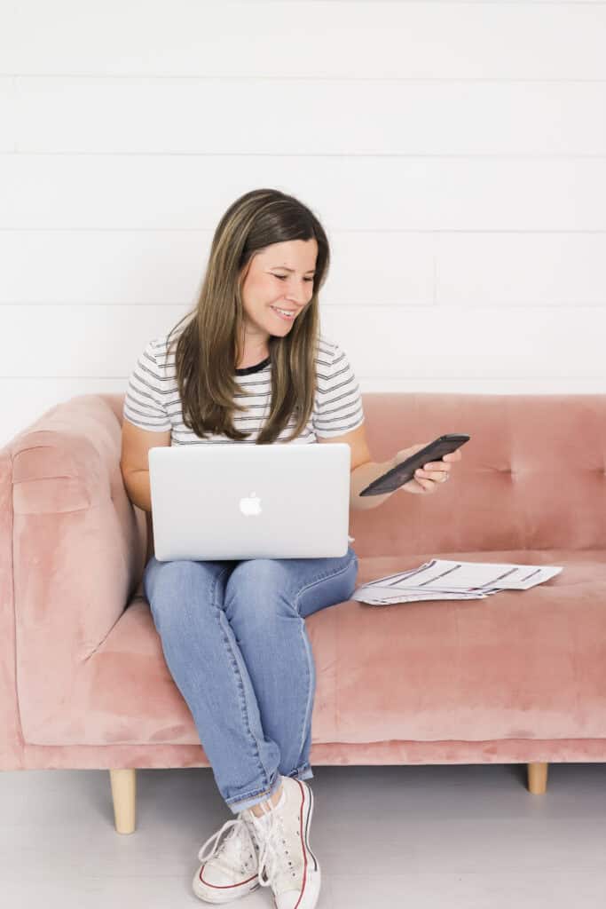 woman using a calculator and computer to review her debt and budget