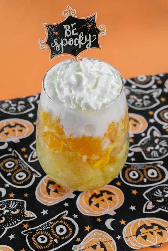 pineapple, oranges, and whipped cream layered in glass cup.