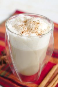 chai latte in glass cup with white foam and cinnamon on top