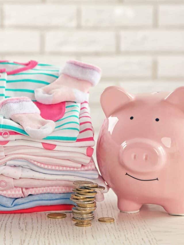 Parenting expenses concept. Pile of baby clothes and piggy bank