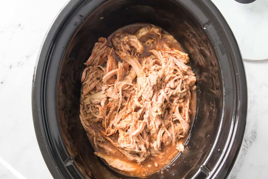 shredded pulled pork with root beer and bbq sauce in slow cooker
