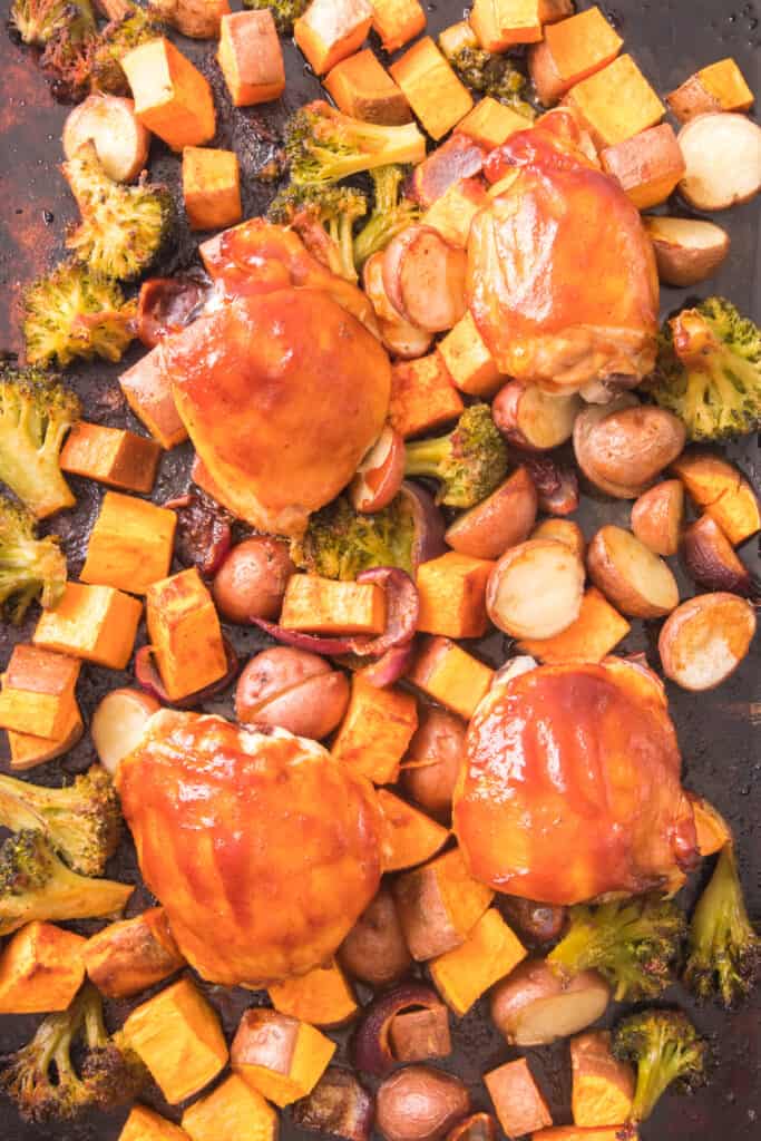 baked sweet potatoes, red potatoes, red onion, frozen broccoli on sheet pan with chicken thigs with bbq sauce