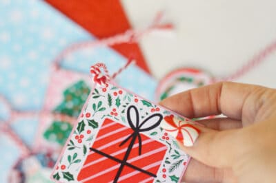 Hand holding a Christmas gift tag showing how the string it attached
