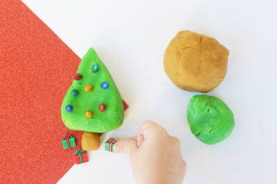 Little hand decorating a play dough christmas tree