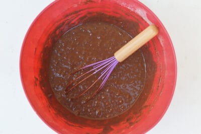 Chocolate muffin batter in a red mixing bowl.