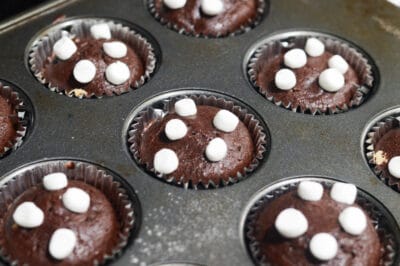 Attaching marshmallow halves to the top of hot chocolate muffins.
