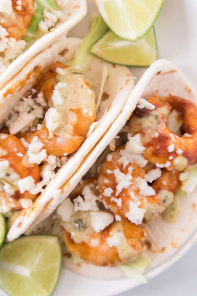 overhead shot of shrimp tacos on plate with limes