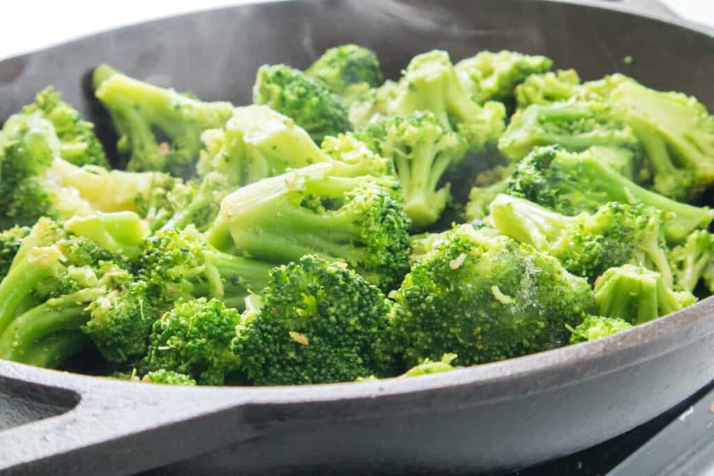 close up of broccoli cooking in cast iron skillet