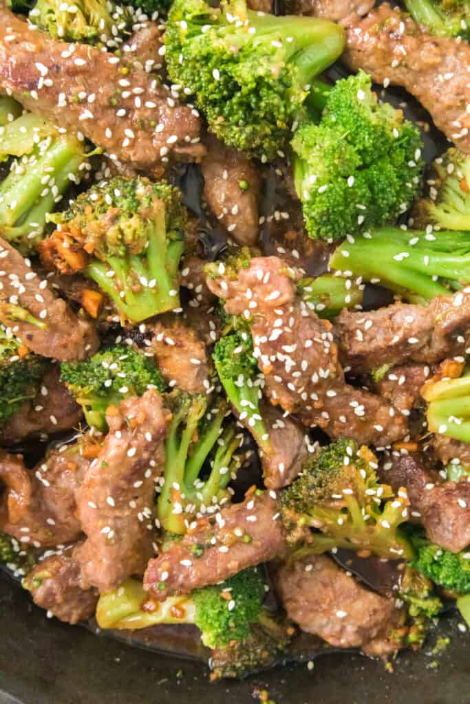 close up of beef and broccoli stir fry recipe topped with white sesame seeds