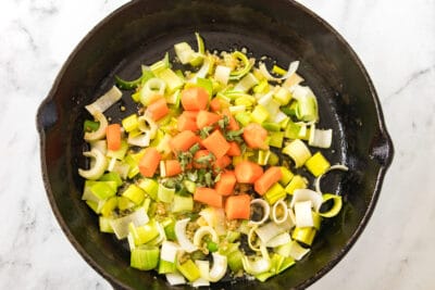 White green and orange veggies in a cast iron skillet