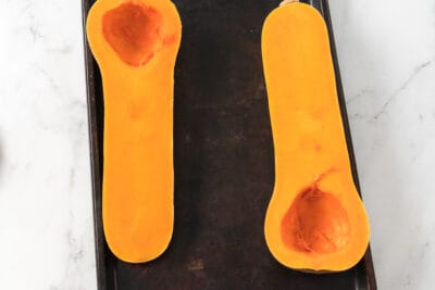 Halved and cleaned butternut squash on a sheet pan