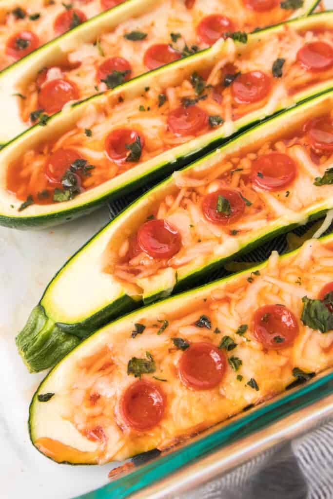 close up vertical shot of pizza zucchini boats in casserole dish