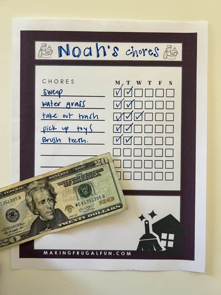 Image of a printable chore chart with a  bill in front of it showing a monetary reward for chores.