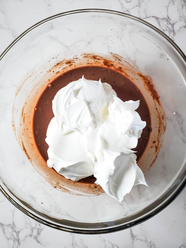 This image shows whipped cream being added to the pudding mix. 