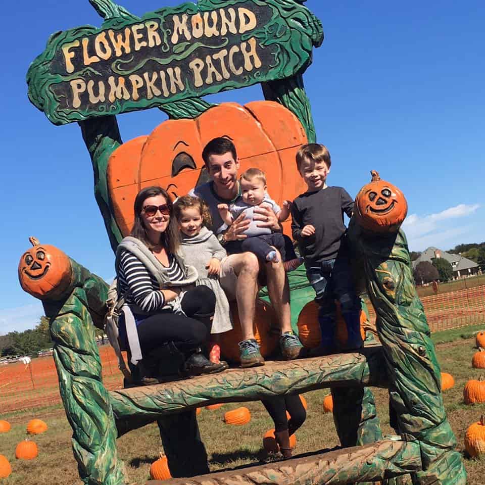 A photo of a family of 5 sitting on a large pumpkin chair at the Flower Mound Pumpkin patch in fort worth. 