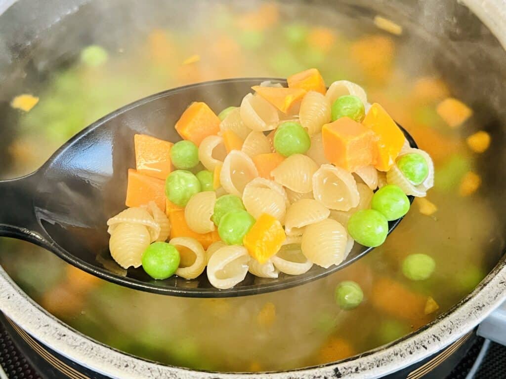 boiling peas and carrots with macaroni noodles.